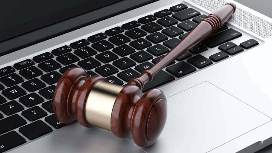 A laptop computer with a judge's gavel lying across the keyboard. 