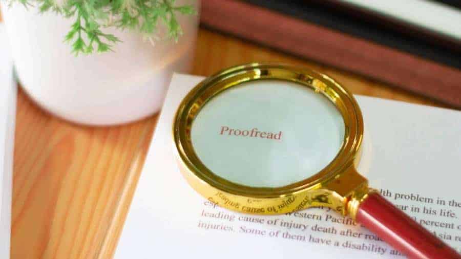 A magnifying glass sits on a paper that needs to be proofread. 
