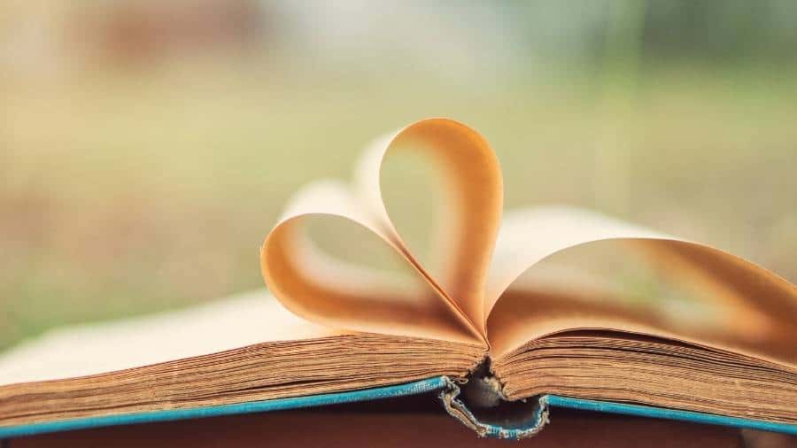 A tattered book with two pages folded toward the center to form a heart shape. 
