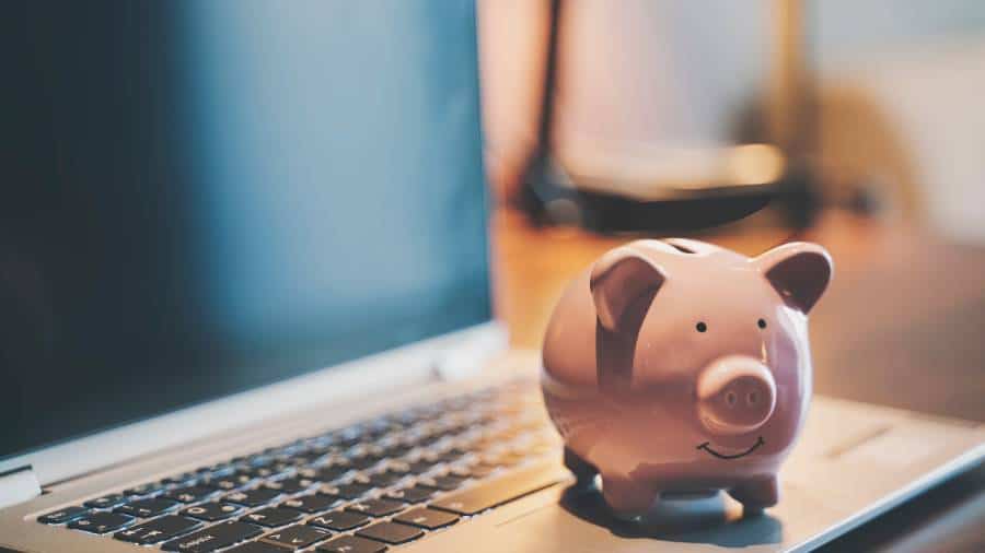 A piggy bank sitting on top of a laptop.
